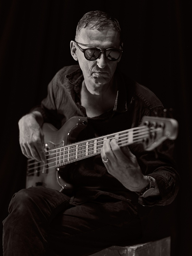 black white portrait of a bassist with sunglasses playing his instrument